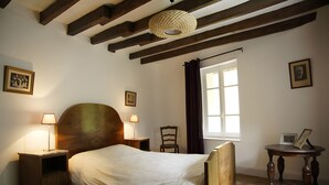 A bedroom with a wooden bed, two bedside lamps, a window with curtains, and a framed picture on the wall. - Cottage "Le Moulin de Laval" with Private Terrace, Wi-Fi, and Air Conditioning (Saint-Priest-des-Champs)