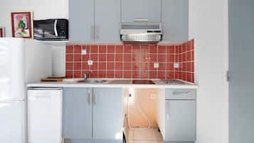 Una cocina compacta con microondas, horno y lavaplatos.