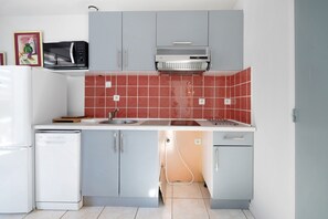 A compact kitchen with a microwave, oven, and a sink.