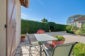 A patio with a table and chairs, a gravel path, and a neatly trimmed hedge.