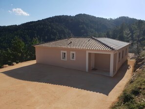 A single-story building with a tiled roof, a small porch, and a paved driveway. - Villa Les Cigales: Mountain View, Wi-Fi, Air Conditioning (Chamborigaud)