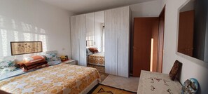 A bedroom with a bed, a wardrobe, a door, and a wall-mounted picture.