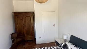 Une chambre à coucher comprenant un lit, une armoire, une chaise, une table de chevet avec une lampe et un luminaire suspendu.