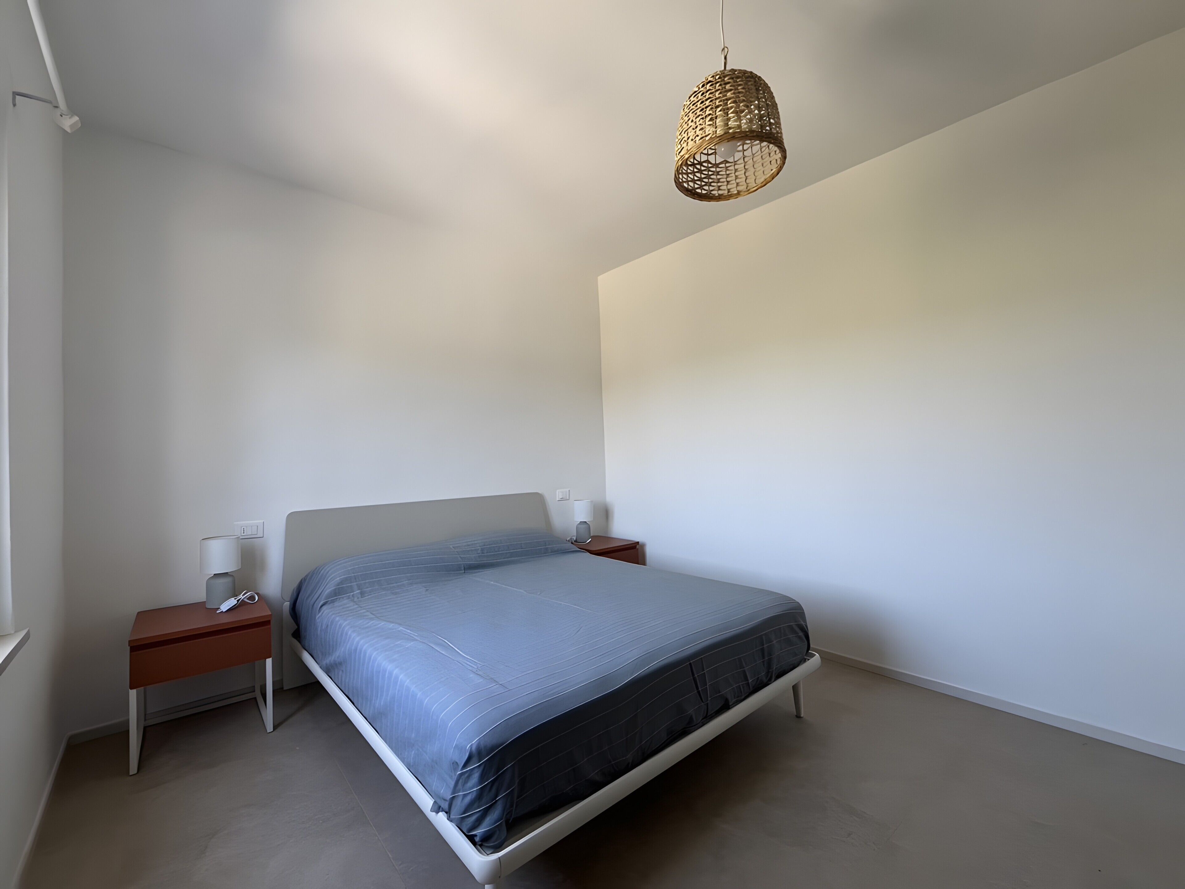 Une chambre à coucher avec un lit, des tables de chevet, une lampe et un luminaire suspendu.