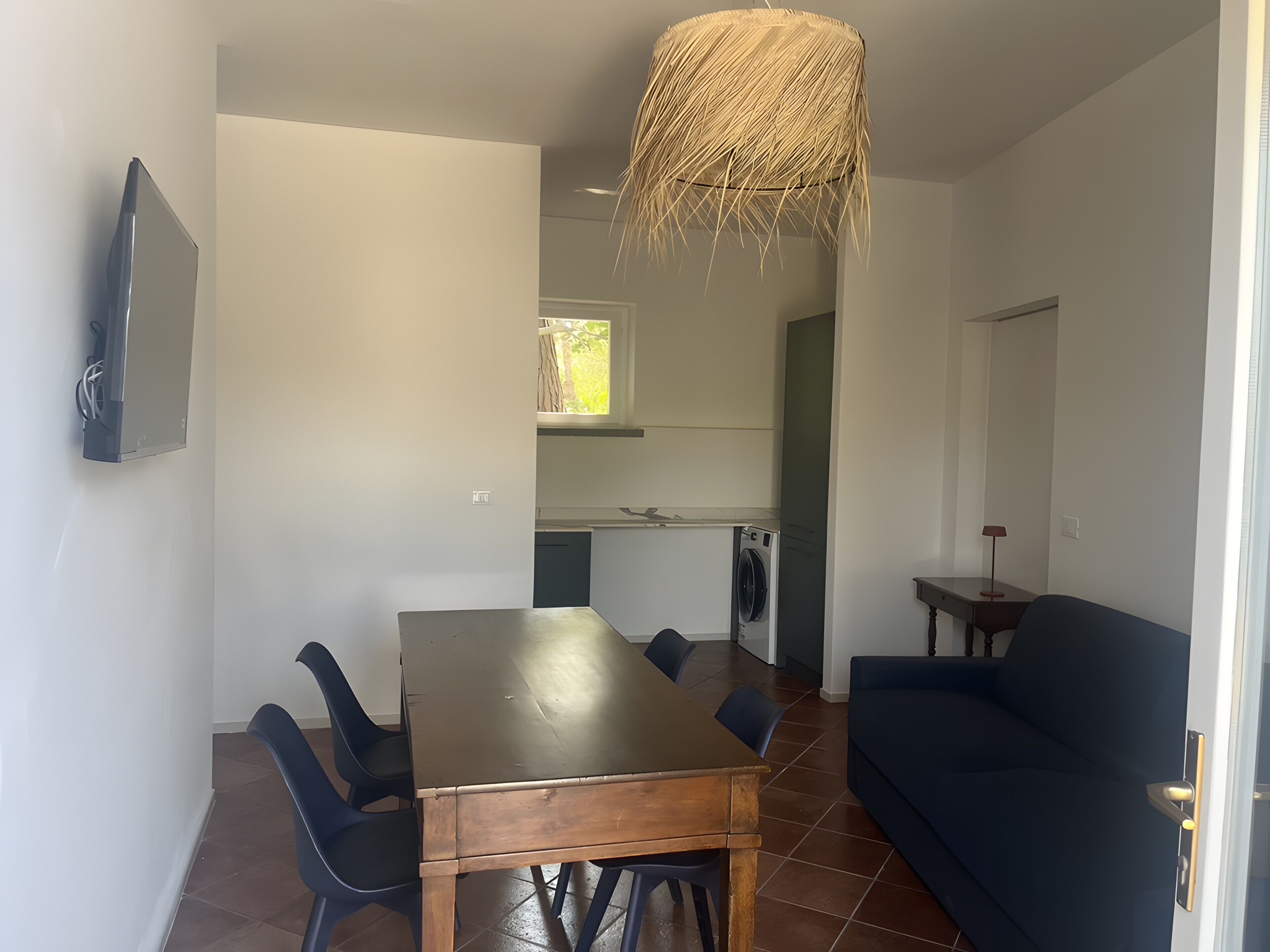 Un coin repas avec une table et des chaises en bois, un canapé bleu et un luminaire suspendu.