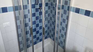Box doccia con porta in vetro e bidet bianco.