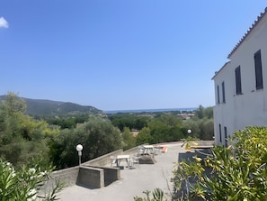 A rooftop terrace with outdoor seating and a view of a coastal landscape. - Holiday Home 'Il Casalino - Bilo 1' with Sea View and Air Conditioning (Marina di Campo)