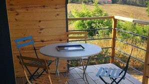 A wooden deck with a table and chairs, overlooking a rural landscape.