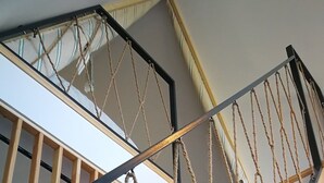 A wooden staircase with a rope handrail and metal balusters.