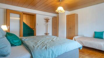 Un dormitorio con una cama, dos mesitas de noche, un perchero y un armario de madera.