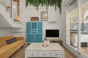 Una sala de estar con un sofá, una mesa de centro, un televisor y un mueble.