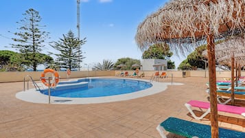 Una piscina en la azotea con diseño circular, rodeada de sillones de descanso y un flotador.