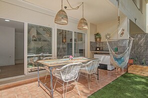 Un patio exterior con mesa y sillas, una hamaca y una pequeña cocina.