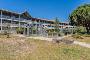 Un hôtel à plusieurs étages doté de balcons, d’une cour intérieure et d’un grand arbre.