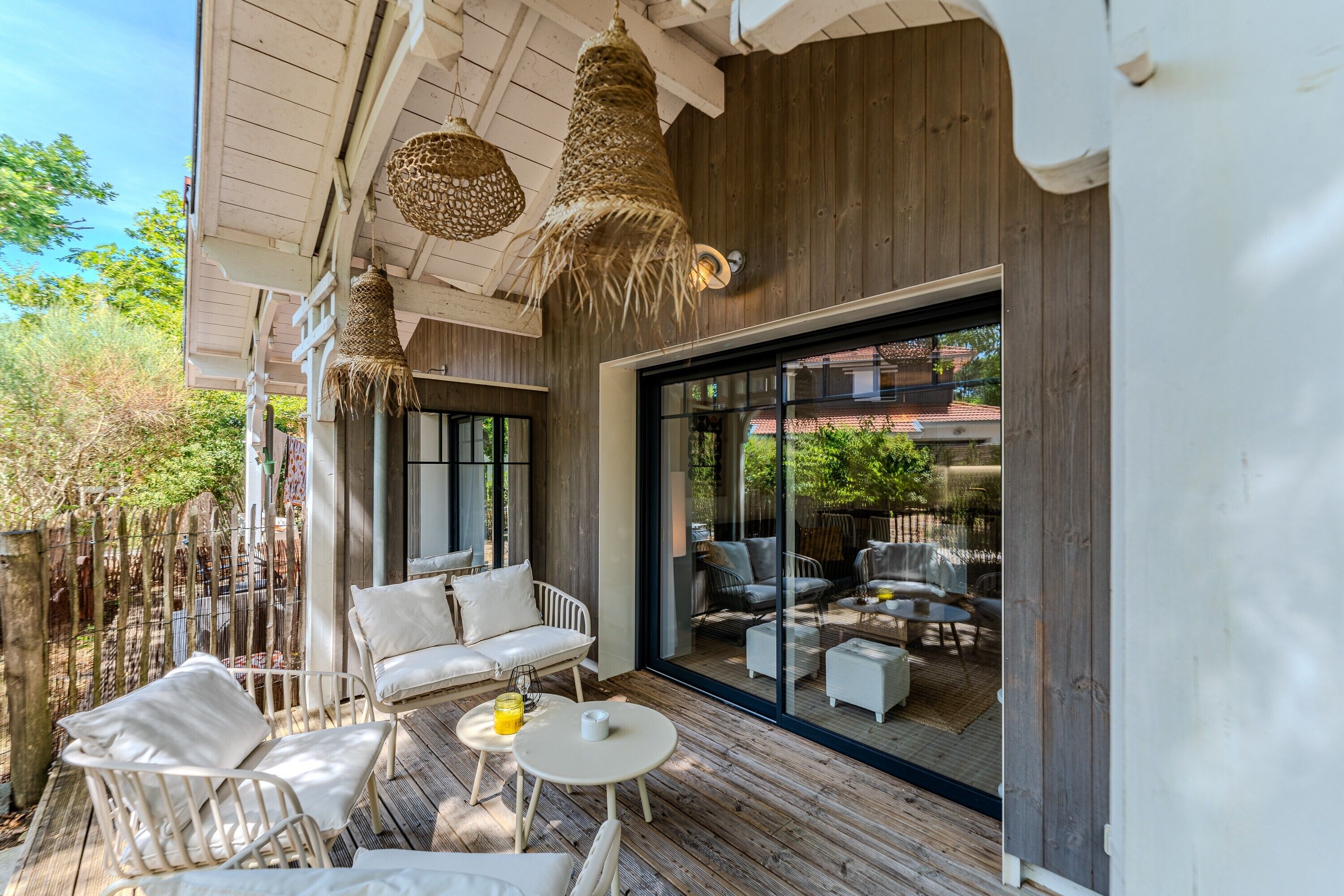 An outdoor seating area with white furniture and a glass door leading to a view of a residential area.