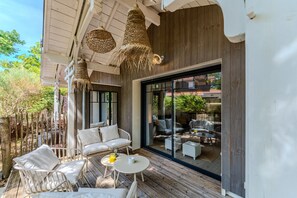 An outdoor seating area with white furniture and a glass door leading to a view of a residential area.