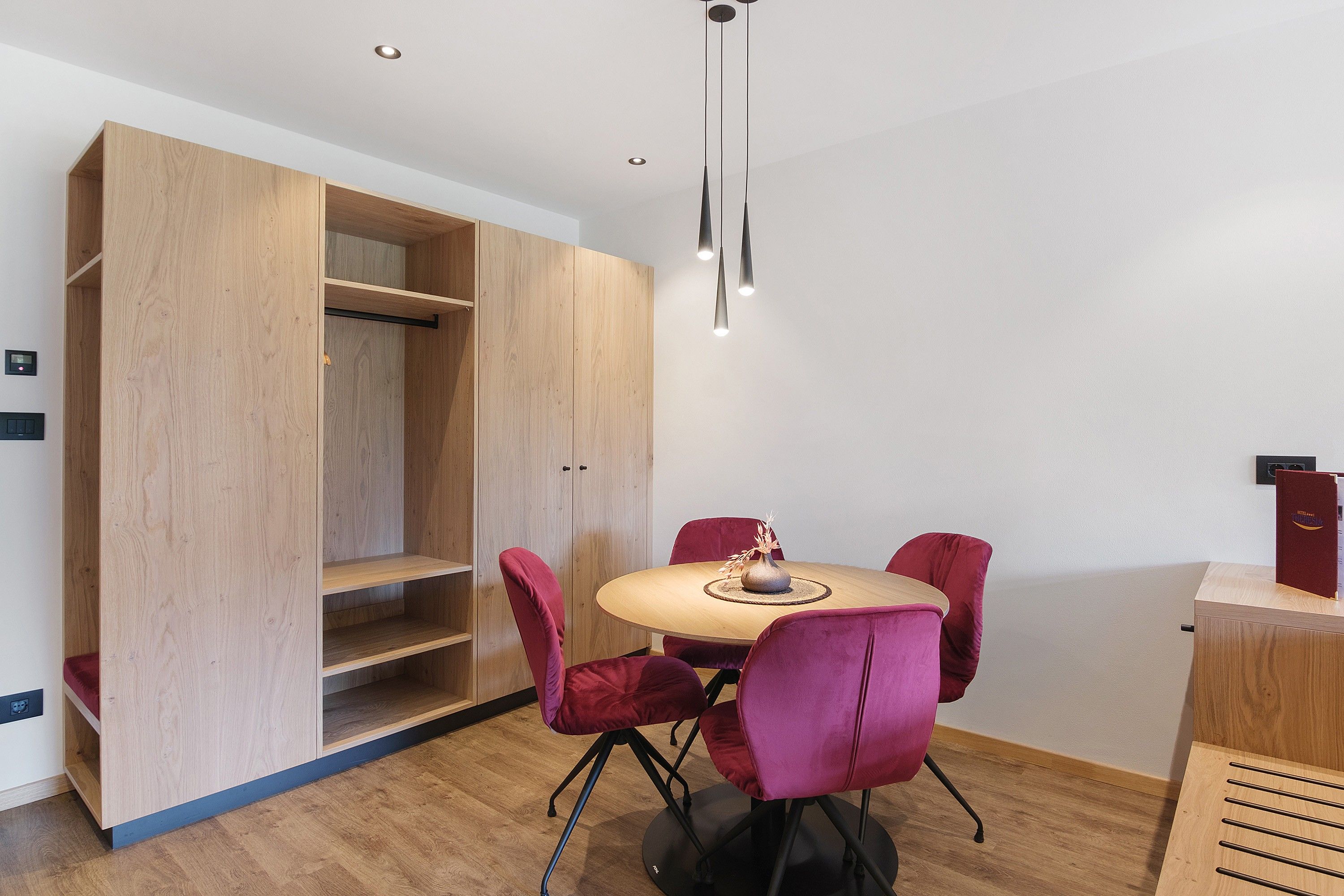 Ein modernes Zimmer mit einem Holzesstisch, roten Stühlen und einem Einbauschrank.