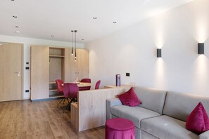 A modern interior with a wooden desk, red chairs, a grey sofa, and a wooden wardrobe. - Apartment at Hotel and Residences Theresia with Mountain View and Private Terrace (St. Leonhard in Passeier)