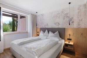 Camera da letto moderna con un letto grande, una testata in legno e vista sul verde.