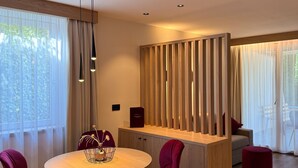 Un comedor moderno con una mesa redonda, sillas rojas, un separador de madera y vistas al exterior.