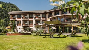 Un hotel con varios balcones, mobiliario exterior y un jardín bien cuidado.