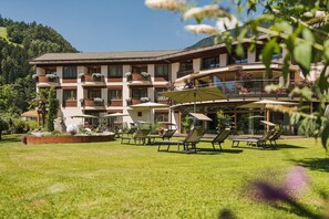 Ein Hotel mit mehreren Balkonen, Sitzgelegenheiten im Freien und einem gepflegten Garten.