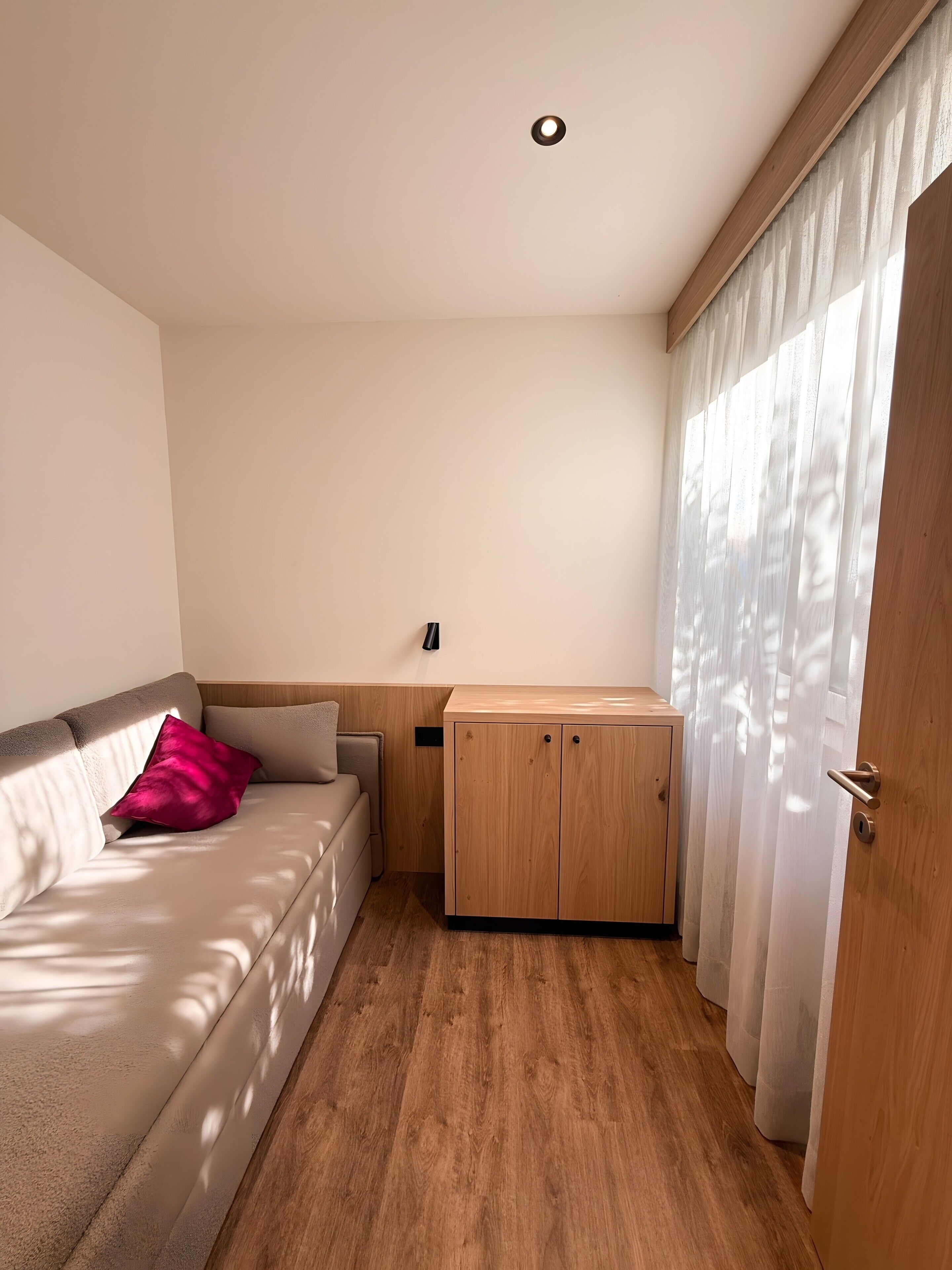 A room with a sofa, a wooden cabinet, and a door with curtains.