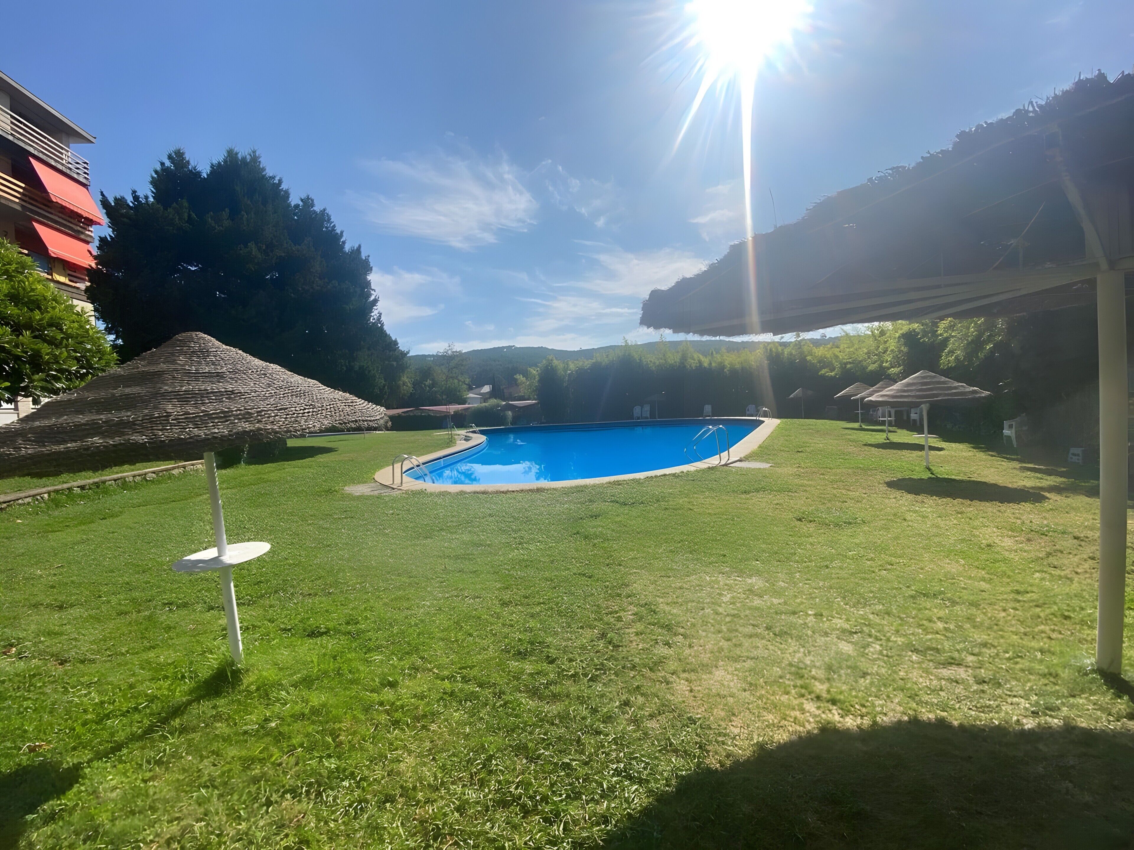 Ein Schwimmbecken, umgeben von Gras, mit blauem Himmel darüber.
