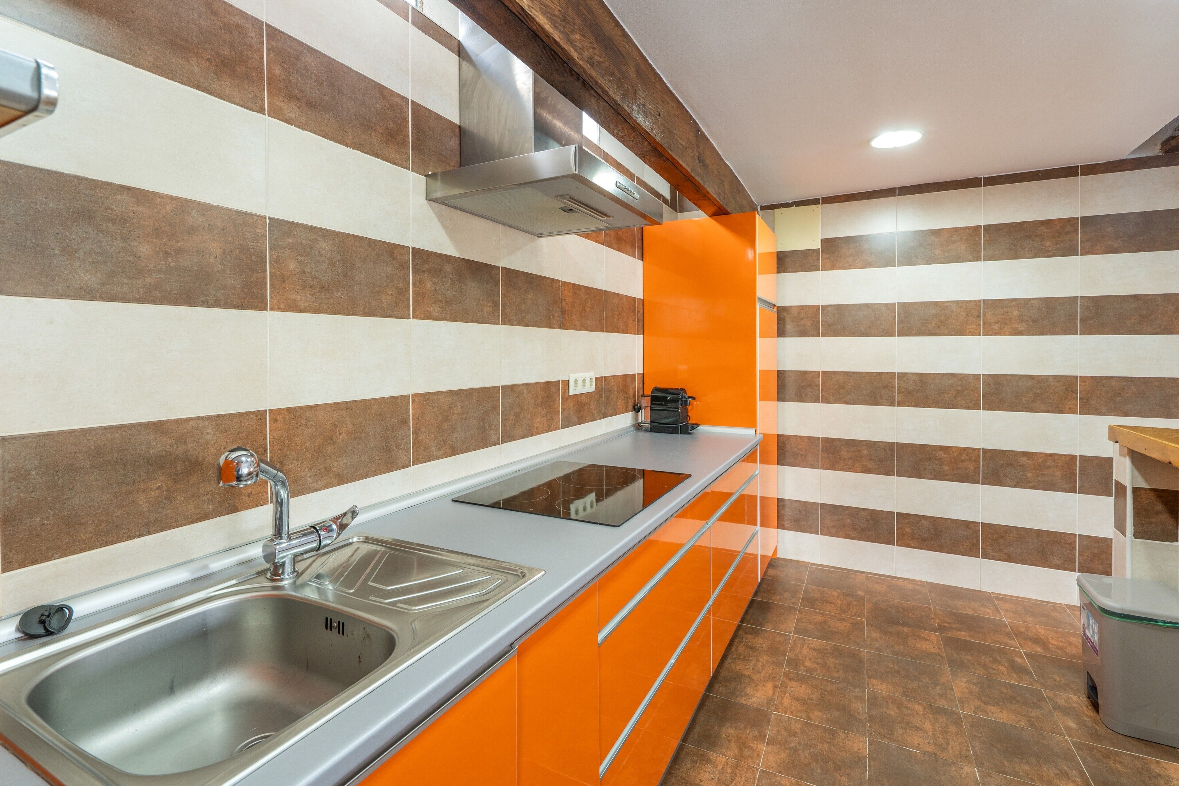 Una cocina moderna con un lavamanos de acero inoxidable, horno empotrado y una encimera con cafetera.