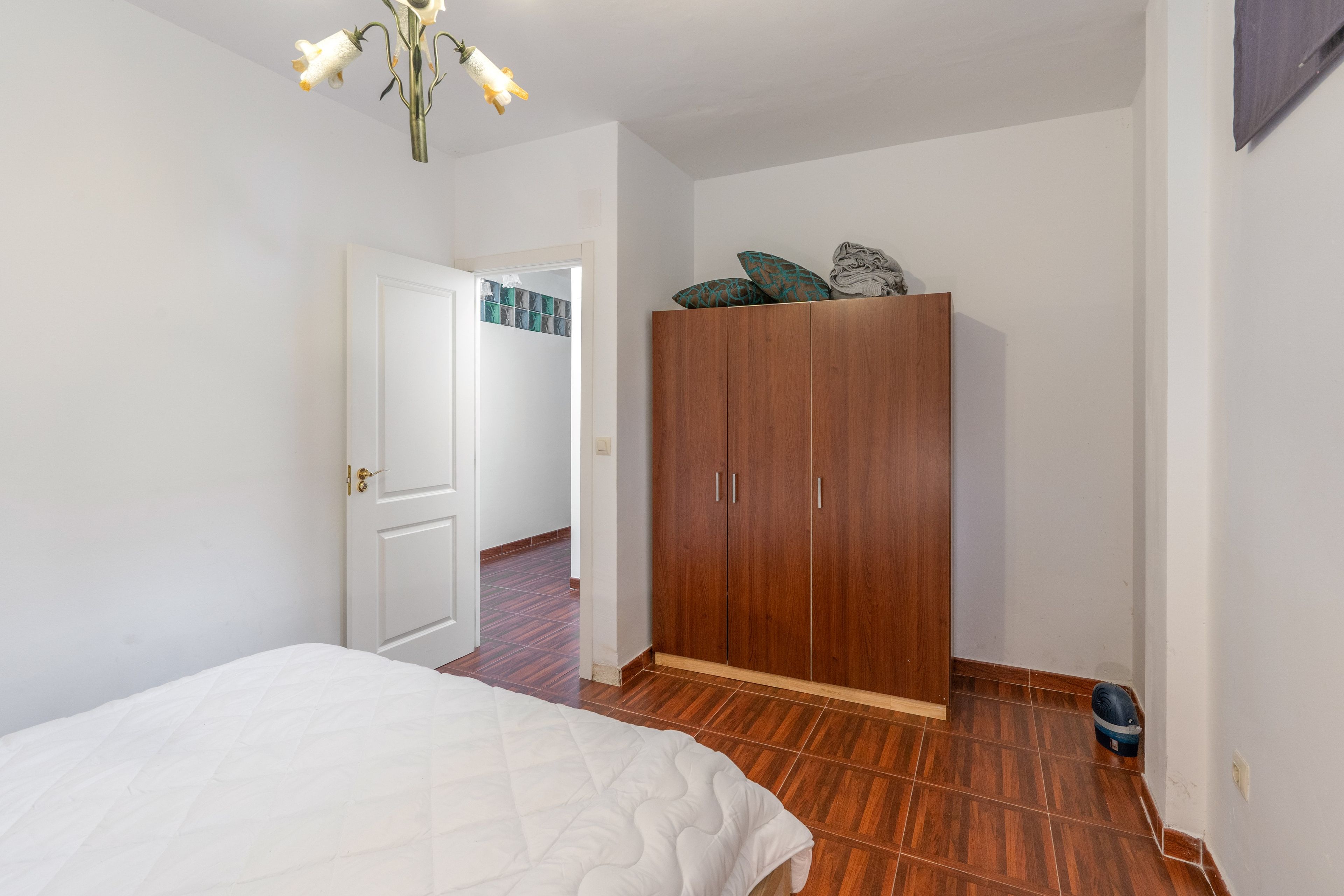 Un dormitorio con una cama, un armario y una puerta que da a otra habitación.