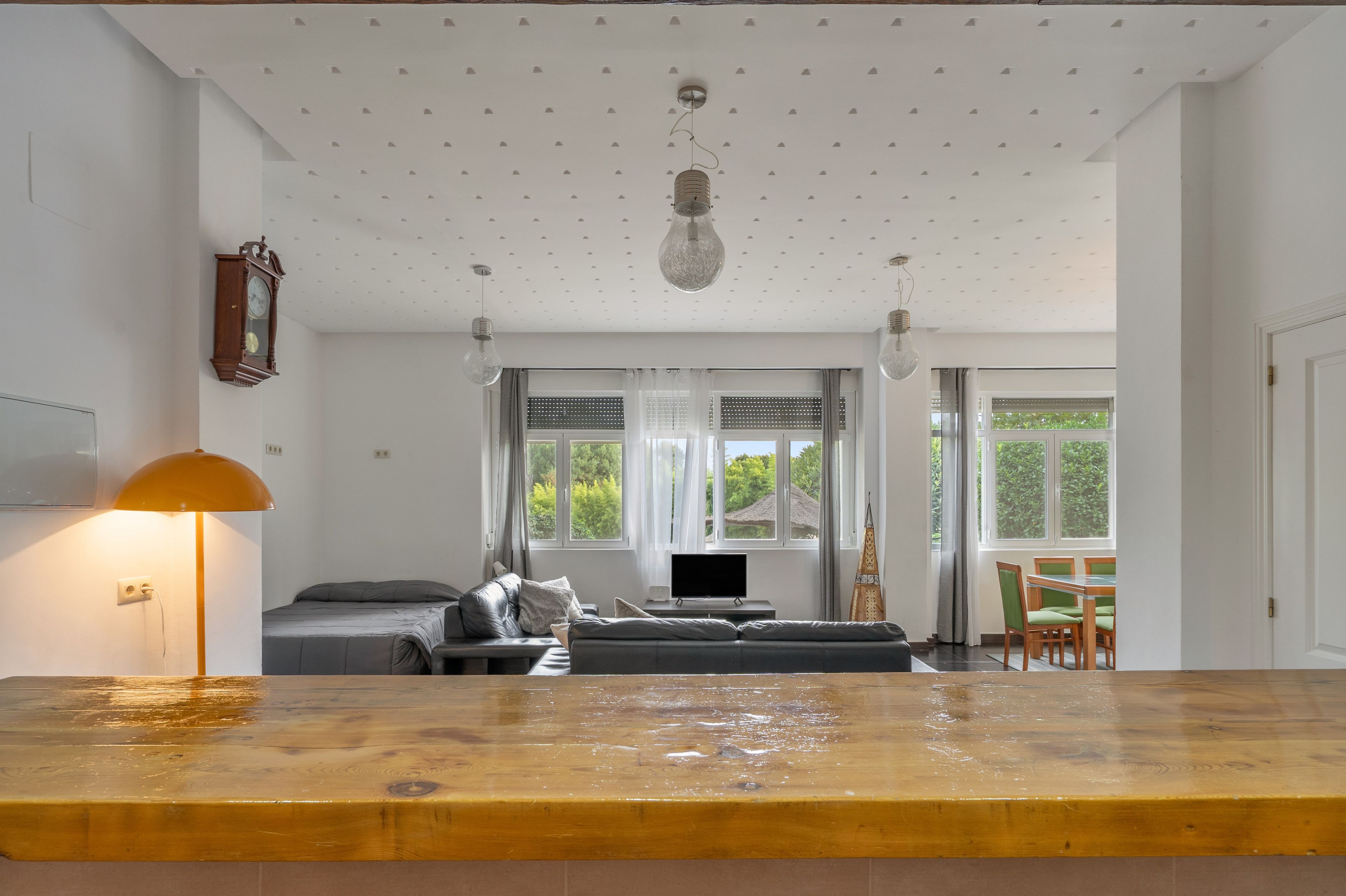 Een moderne woonkamer met een bank, een televisie en een eethoek met stoelen.