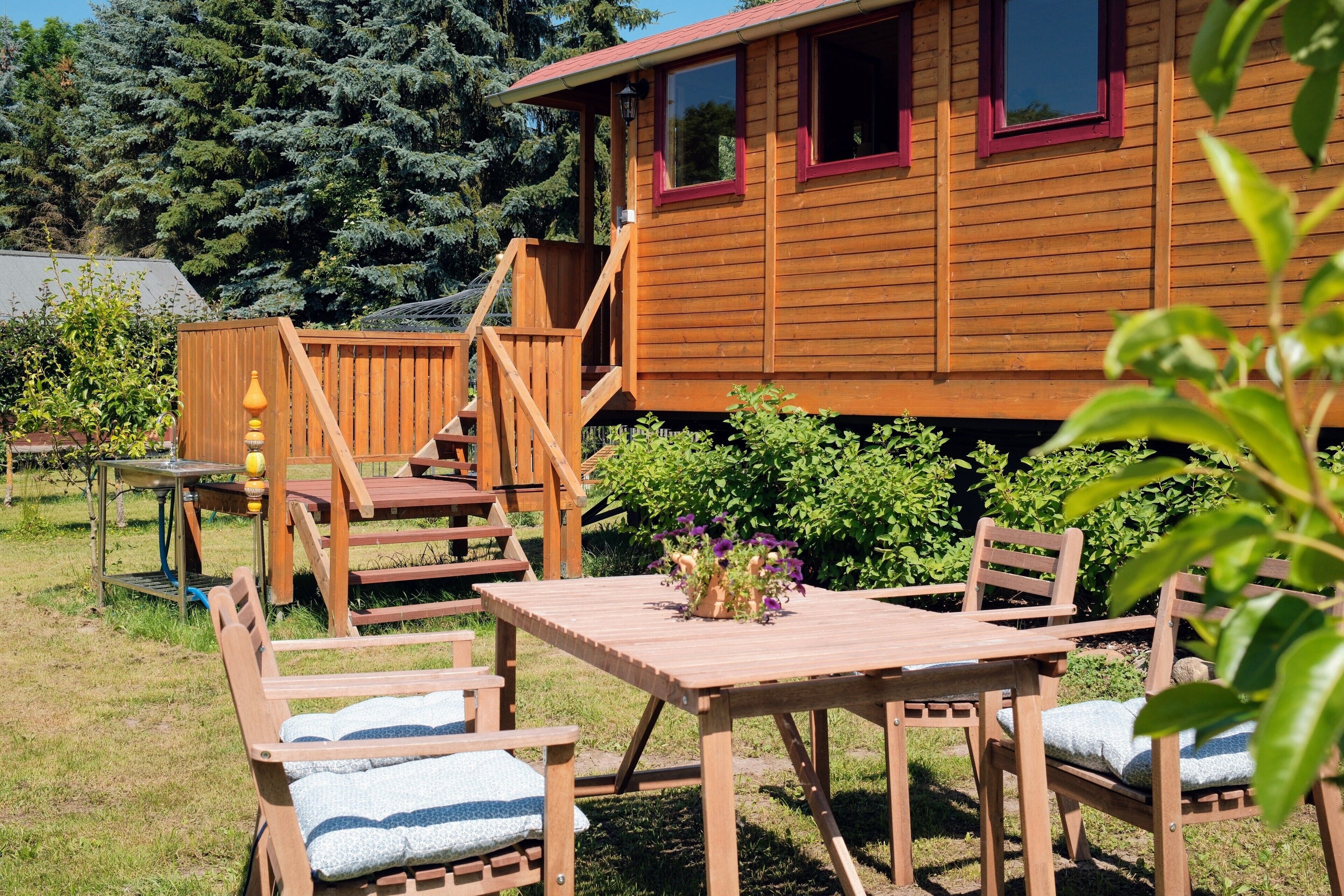 A wooden cabin with a deck, outdoor seating, and a garden area.