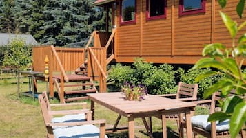 A wooden cabin with a deck, outdoor seating, and a garden area.