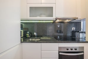 A modern kitchen with a stainless steel sink, a built-in oven, and a microwave. - Holiday Home 'Apartamento Nascimento' with Shared Pool, Private Terrace and Air Conditioning (Santa Luzia)