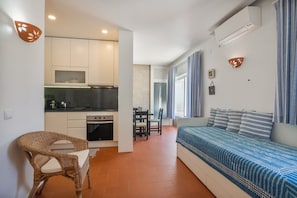 En kompakt bolig med tekøkken, spiseplads og opholdsområde med sofa.