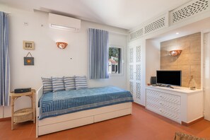 A bedroom with a bed, a TV, a window with curtains, and a wall-mounted light fixture. - Holiday Home 'Apartamento Nascimento' with Shared Pool, Private Terrace and Air Conditioning (Santa Luzia)