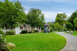 A park with a pathway, benches, and a building with a blue structure. - Apartment 'Haus Kuhlmann Mit Schlafsofa' with Mountain View, Shared Garden and Wi-Fi (Landkreis Goslar)