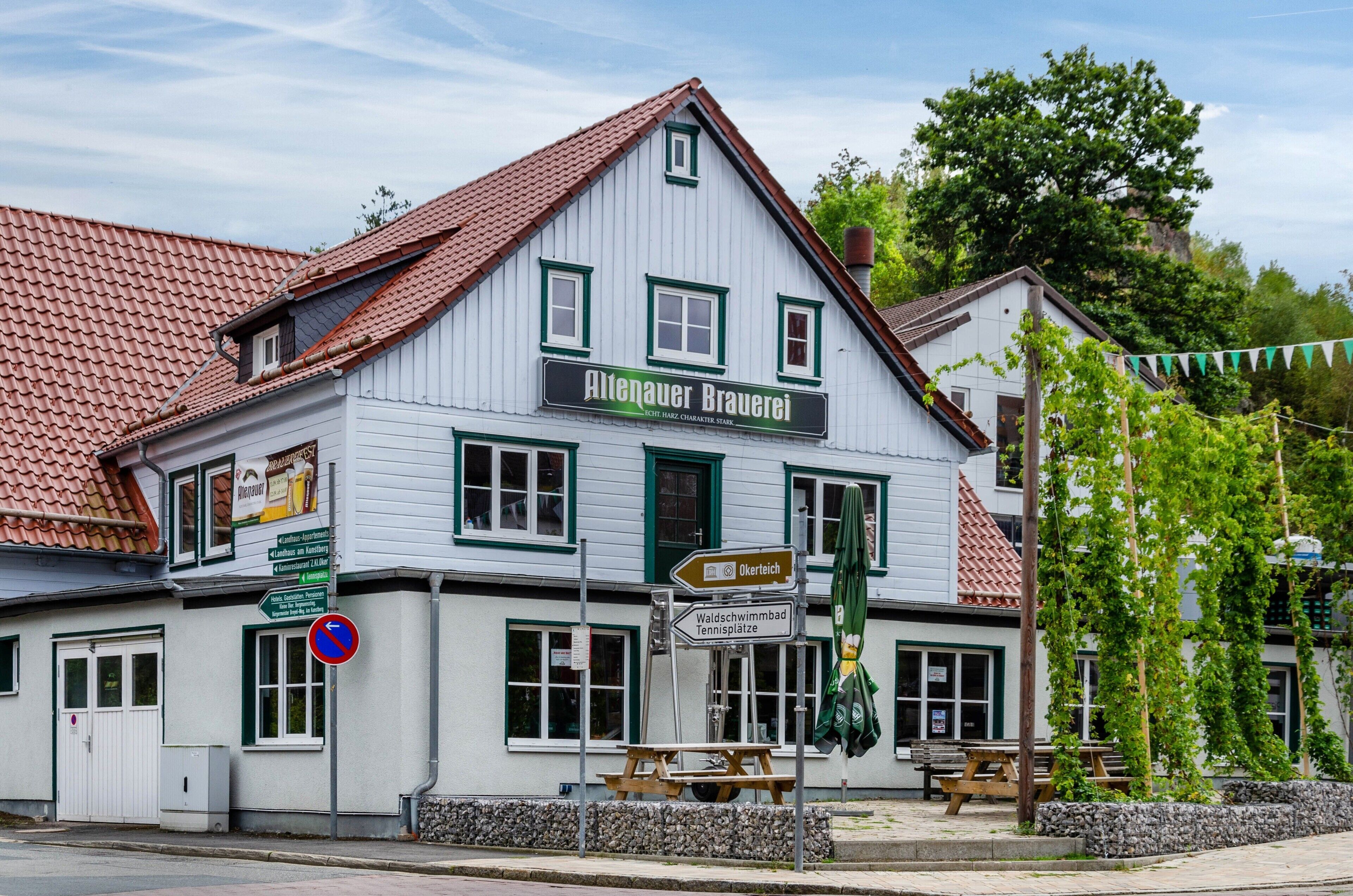 Um edifício tradicional com uma placa indicando 'Altenauer Brauerei' e sinais de direção para atrações locais.