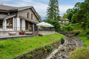 A building with a terrace, outdoor seating, and a stone wall. - Apartment 'Haus Kuhlmann Mit Schlafsofa' with Mountain View, Shared Garden and Wi-Fi (Landkreis Goslar)