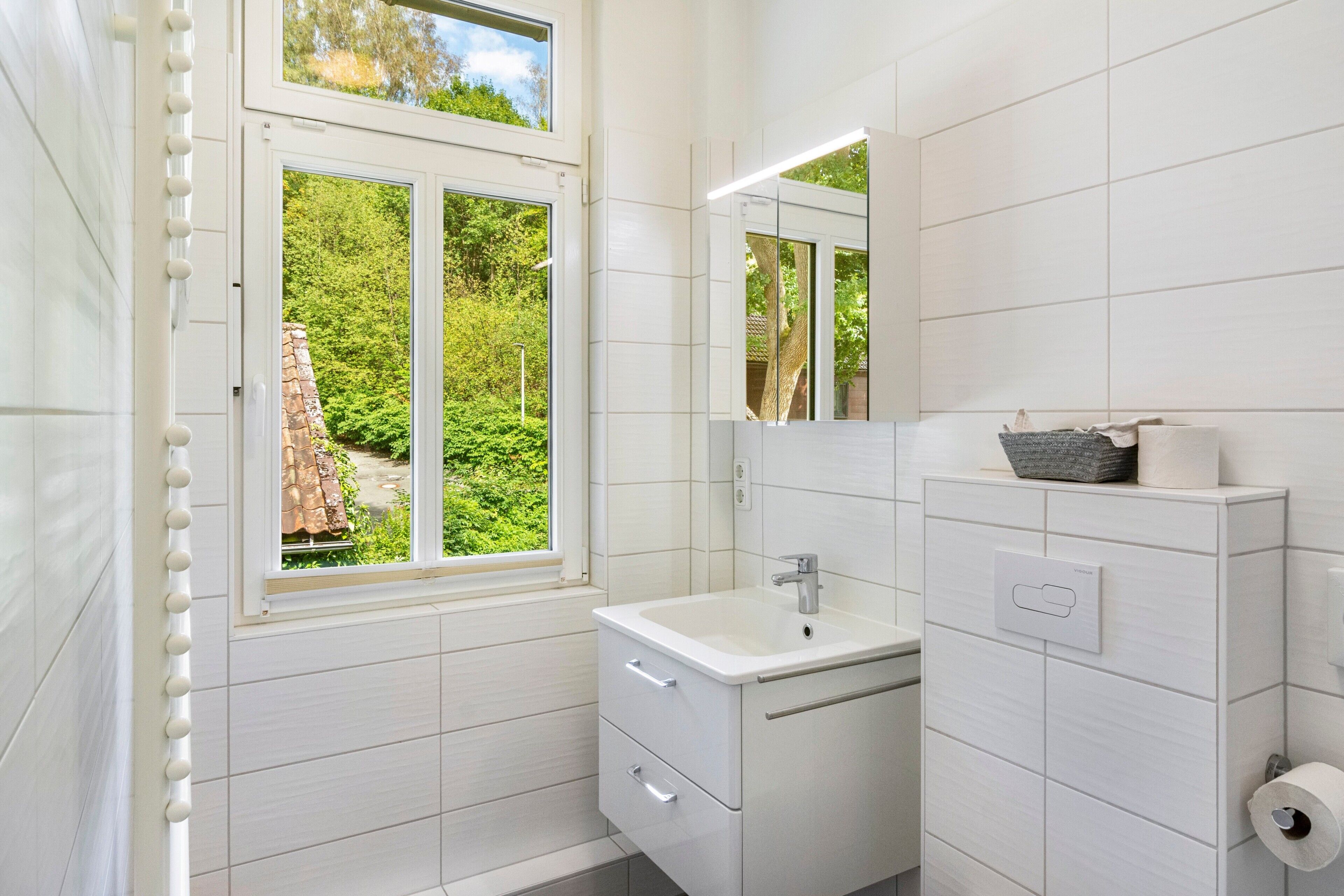 Ein modernes Badezimmer mit Fenster, Waschbecken und Spiegel.