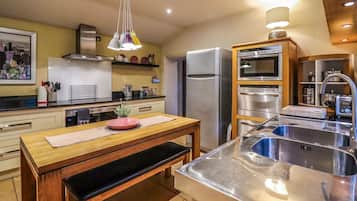 A modern kitchen with stainless steel appliances, a wooden dining table, and a built-in oven.