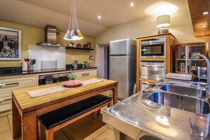 Una cocina moderna con electrodomésticos de acero inoxidable, una mesa de comedor de madera y un horno empotrado.