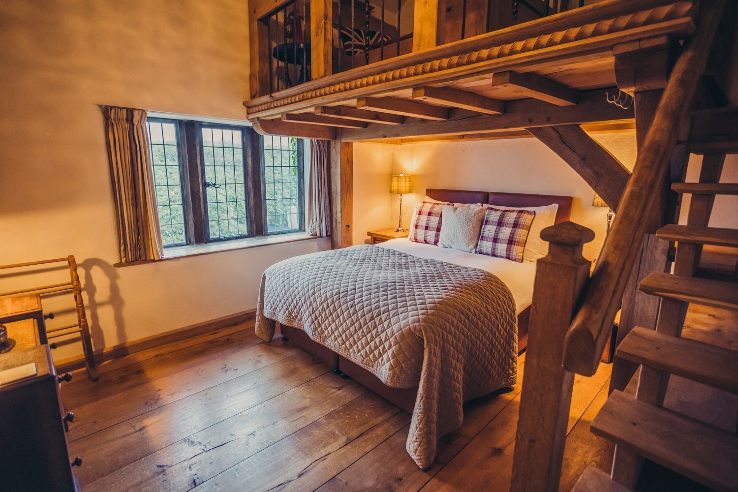 A bedroom with a wooden bed, a nightstand, a lamp, and a window with curtains.