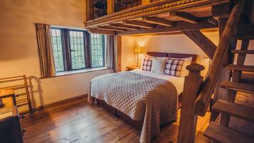 A bedroom with a wooden bed, a nightstand, a lamp, and a window with curtains.