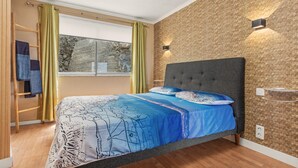 Une chambre à coucher avec un lit, une fenêtre, une lampe fixée au mur et un porte-serviettes.