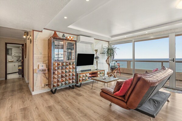 A modern living room with a large TV, a wooden cabinet, and a leather sofa.