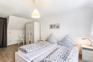 A bedroom with a bed, bedside table, lamp, wardrobe, chair, and a framed picture on the wall. - Apartment 'Fewo Wrede Am Sauerland-Radring 2' with Mountain View, Balcony and Wi-Fi (Eslohe)