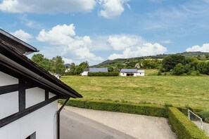 A rural landscape with a building featuring a sloped roof and a paved entrance. - Apartment 'Fewo Wrede Am Sauerland-Radring 2' with Mountain View, Balcony and Wi-Fi (Eslohe)
