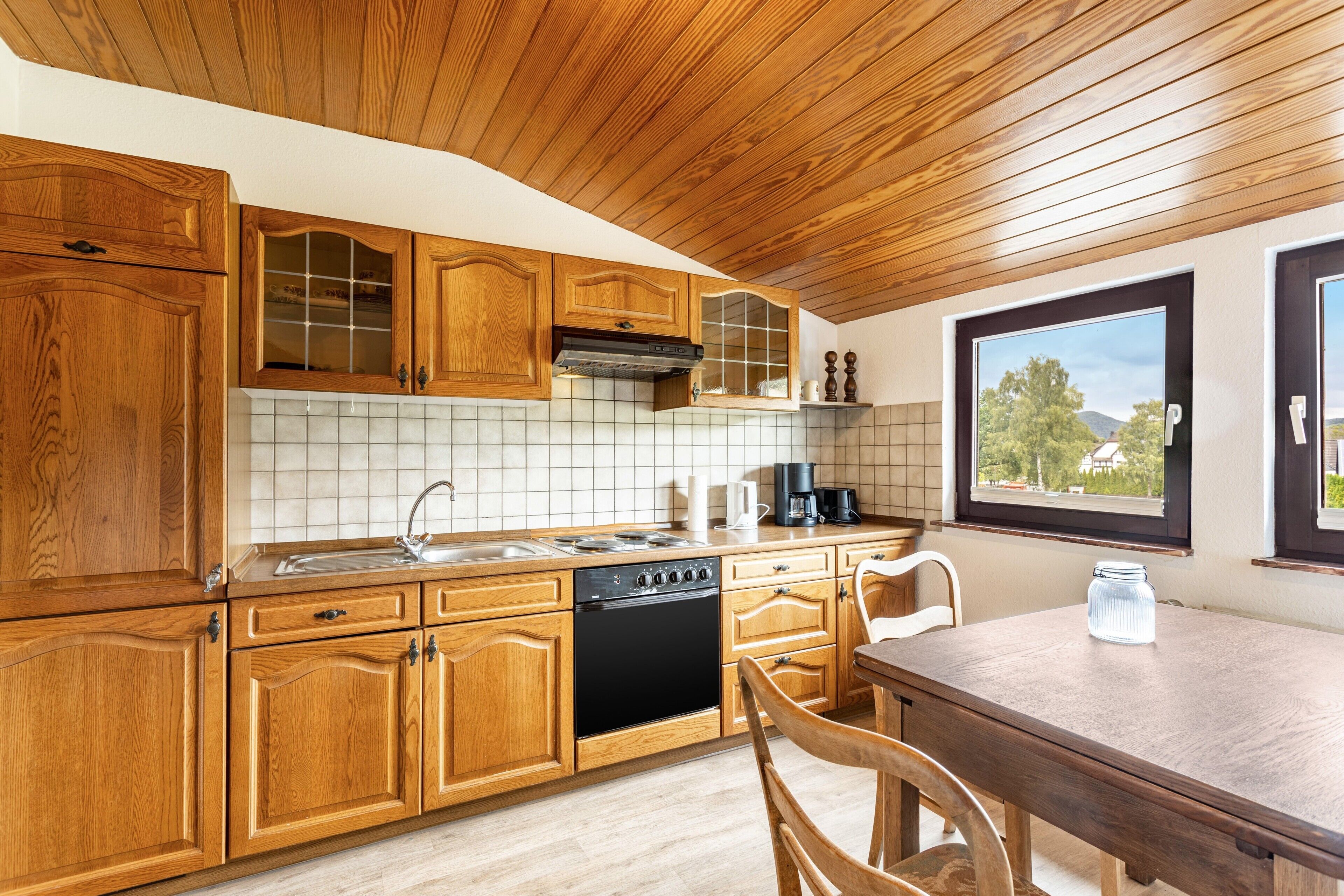 Une cuisine avec des meubles en bois, un lave-vaisselle et une fenêtre donnant sur un beau paysage.