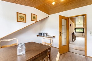 A dining area with a wooden table, chairs, and a jar on the table. There is a door leading to another room with a window. - Apartment 'Fewo Wrede Am Sauerland-Radring 2' with Mountain View, Balcony and Wi-Fi (Eslohe)